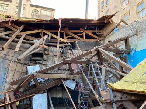 Rubble and exposed wooden beams from a building under demolition, view from below.
